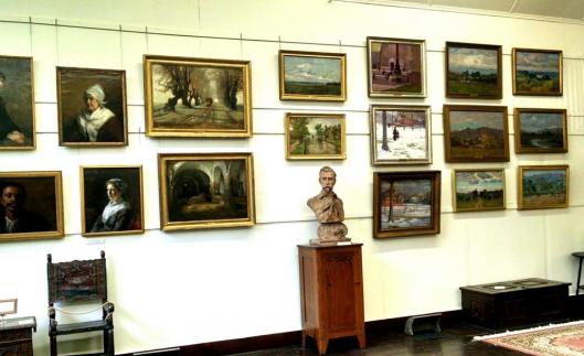 Inside T. C. Steele's studio. The portraits highlight his work prior to his exposure to impressionism. The landscapes illustrate how his painting style changed over time.